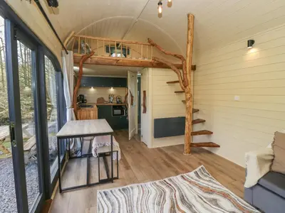 a living room with a spiral staircase in a tiny house at Binsey Lodge in Wigton