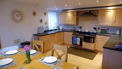 a kitchen with a table and a clock on the wall at 9 Millburn Street in Kirkcudbright
