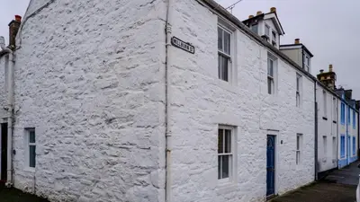a white building with a street sign on it at 9 Millburn Street in Kirkcudbright