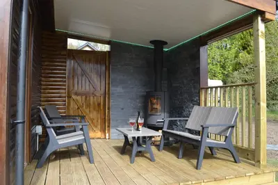 a deck with two chairs and a table and a stove at The Tranquil Orchard in Dumfries