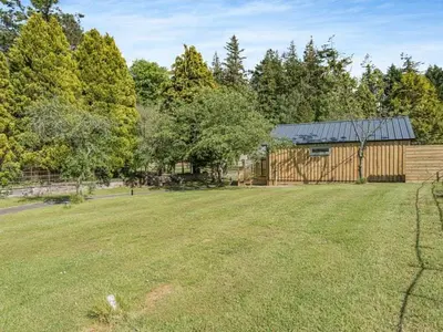 an empty yard with a wooden barn in the background at The Tranquil Orchard in Dumfries