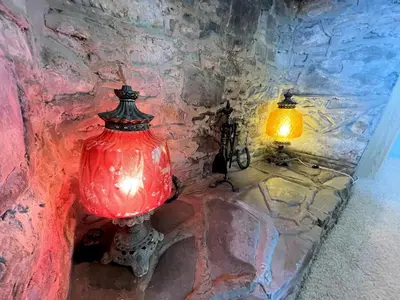 a red lamp sitting next to a stone wall at Traditional Cottage with Beautiful Views - Pass the Keys in Isle of Whithorn