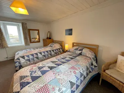 a bedroom with two beds and a chair at Traditional Cottage with Beautiful Views - Pass the Keys in Isle of Whithorn
