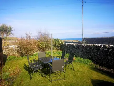 a table and chairs in a yard with a stone wall at Traditional Cottage with Beautiful Views - Pass the Keys in Isle of Whithorn
