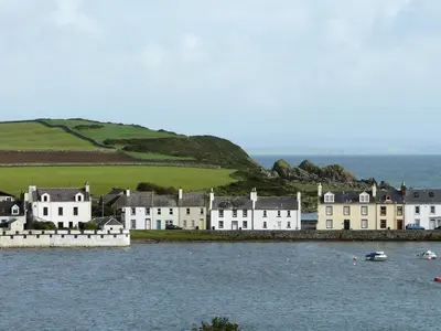 a row of houses on the shore of a body of water at Traditional Cottage with Beautiful Views - Pass the Keys in Isle of Whithorn