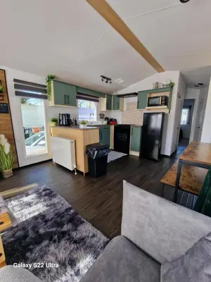 a living room with a couch and a kitchen at Forest Valley Holiday Home in Ballantrae