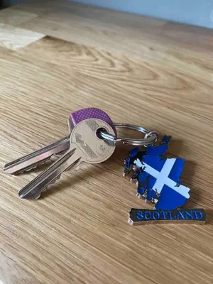 a pair of keys sitting on a wooden table at The Woodhouse Cabin 8 in Moffat