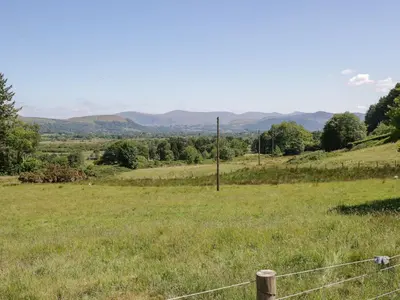 a field with a fence in a field with mountains at Swallow's Nest in Keswick