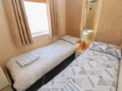 two beds in a small room with a window at New Horizon in Carlisle