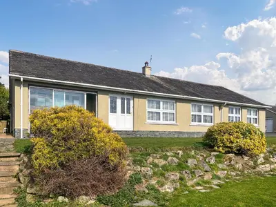 a yellow house with white windows and bushes at Violet Bank in Cockermouth
