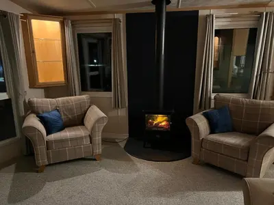 a living room with two chairs and a fireplace at Penny in Whithorn