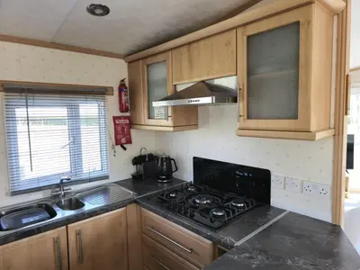 a kitchen with wooden cabinets and a stove top oven at Penny in Whithorn
