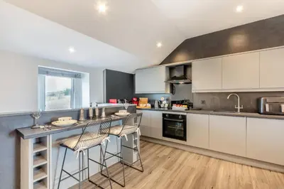 a kitchen with white cabinets and a bar with stools at 1 Bed in Cockermouth oc-s31514 in Embleton