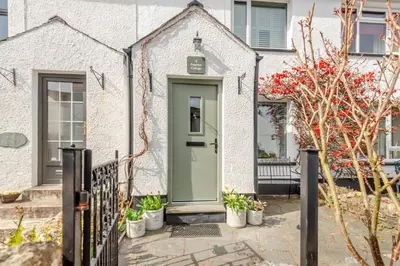 a green door on a white house with potted plants at 2 Bed in Braithwaite oc-p31730 in Braithwaite