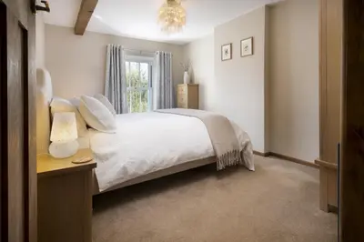 a bedroom with a white bed and a window at Riverside - Quaint County Cottage overlooking the Beck in Caldbeck