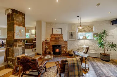 a living room with a fireplace and a table and chairs at Hightae B&B in Hightae