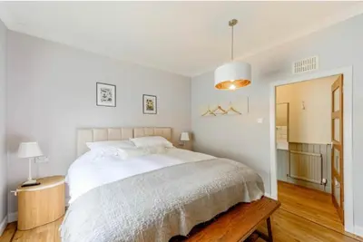 a white bedroom with a large bed and a wooden floor at Hightae B&B in Hightae