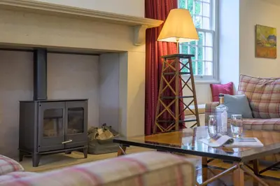 a living room with a fireplace and a table at The School at Mungrisdale in Penrith