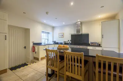 a kitchen with a counter with chairs and a table at The School at Mungrisdale in Penrith