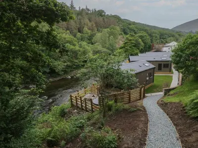 a walkway next to a river next to a building at Dubs Luxury Family Pod in Keswick