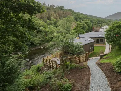 a walkway next to a river next to a building at Hodge Luxury Pod in Keswick
