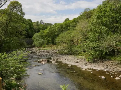 a river with rocks and trees on the side at Hodge Luxury Pod in Keswick