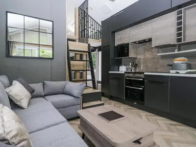 a living room with a couch and a kitchen at Woof Luxury Family Pod in Keswick