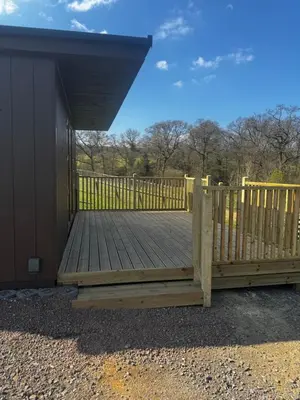 a wooden deck with a fence in front of a house at Country Cabin in Hesket Newmarket