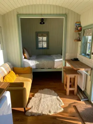 a bedroom with a bed and a couch in a room at Sunset Snug Shepherd hut in Penrith