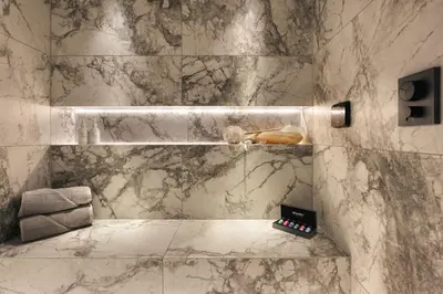 a marble bathroom with a remote control on a shelf at The Sanctuary - Ridgestone in Watermillock