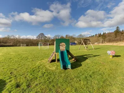 a playground in a field with a swing set at Villa Rabbie Burns Lodge by Interhome in Straiton