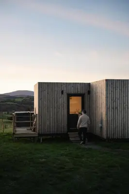 a man is standing outside of a small building at The Byre, Summerhill Farm Stays in Balmaclellan