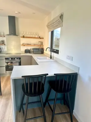 a kitchen with two bar stools at a counter at The Barn, Summerhill Farm Stays in Balmaclellan