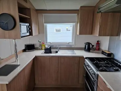 a kitchen with a sink and a stove and a window at Manannan in Maryport