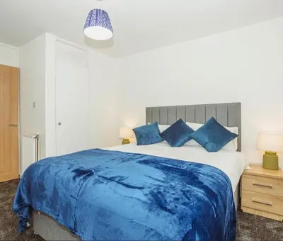 a bedroom with a large bed with blue sheets at Caul View Apartment in Dumfries in Dumfries