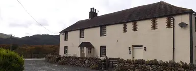 a white building with a fence in front of it at Sandhills Farm in Bassenthwaite