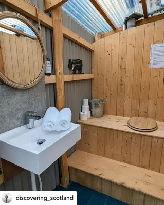 a bathroom with a sink in a wooden building at The Hidden Shepherds Hut- Off Grid Retreat in Castle Douglas