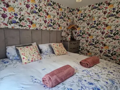 a bedroom with a bed with pillows and floral wallpaper at The Burrow by Blake View Holidays a peaceful boutique retreat 3 miles from Ennerdale- standard twin or super-king bed available in Rowrah