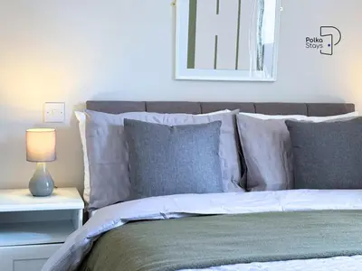 a bed with gray and white pillows and a mirror at The Stables Lake District Retreat by PolkaStays in Troutbeck