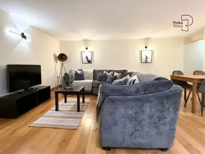 a living room with a blue couch and a tv at The Stables Lake District Retreat by PolkaStays in Troutbeck