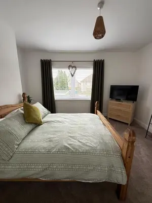a bedroom with a bed and a television and a window at Modern 2 bed with secure driveway in Dumfries