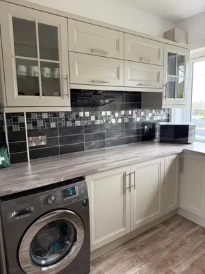 a kitchen with white cabinets and a washer at Modern 2 bed with secure driveway in Dumfries