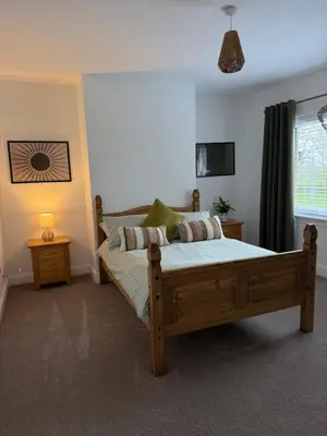 a bedroom with a wooden bed and a window at Modern 2 bed with secure driveway in Dumfries
