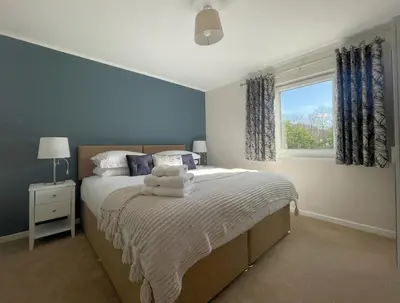 a bedroom with a bed with blue walls and a window at Farmers Retreat in Keswick