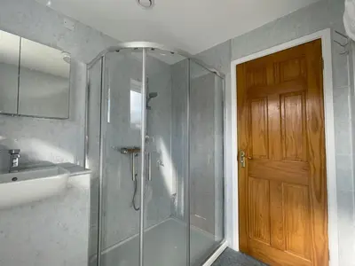 a bathroom with a shower and a sink and a door at Farmers Retreat in Keswick
