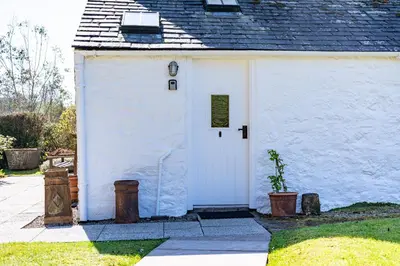 a small white house with a white door at Cross Cottage in Gatehouse of Fleet