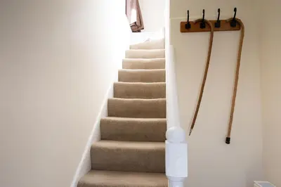 a stairway with aige carpeted stair case at Cross Cottage in Gatehouse of Fleet