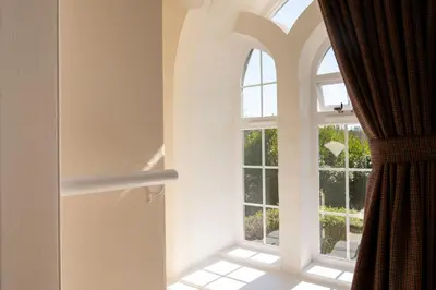 an arched window in a room with a curtain at Cross Cottage in Gatehouse of Fleet