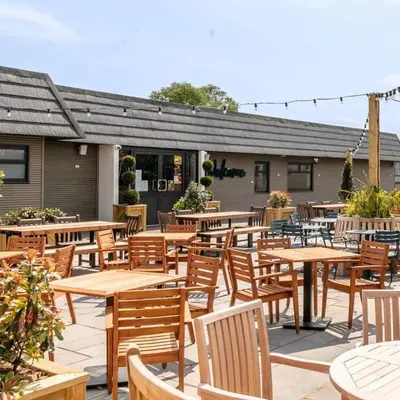an outdoor patio with wooden tables and chairs at Shoreline Stay in Port Carlisle