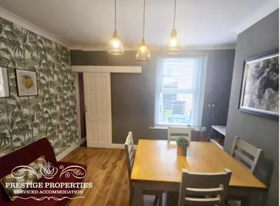 a dining room with a table and a table and chairs at Harcourt by Prestige Properties SA in Workington